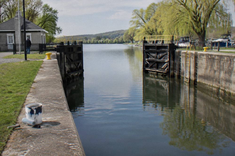 An Erie Canal lock chamber with gates open and water calm at the start of the season