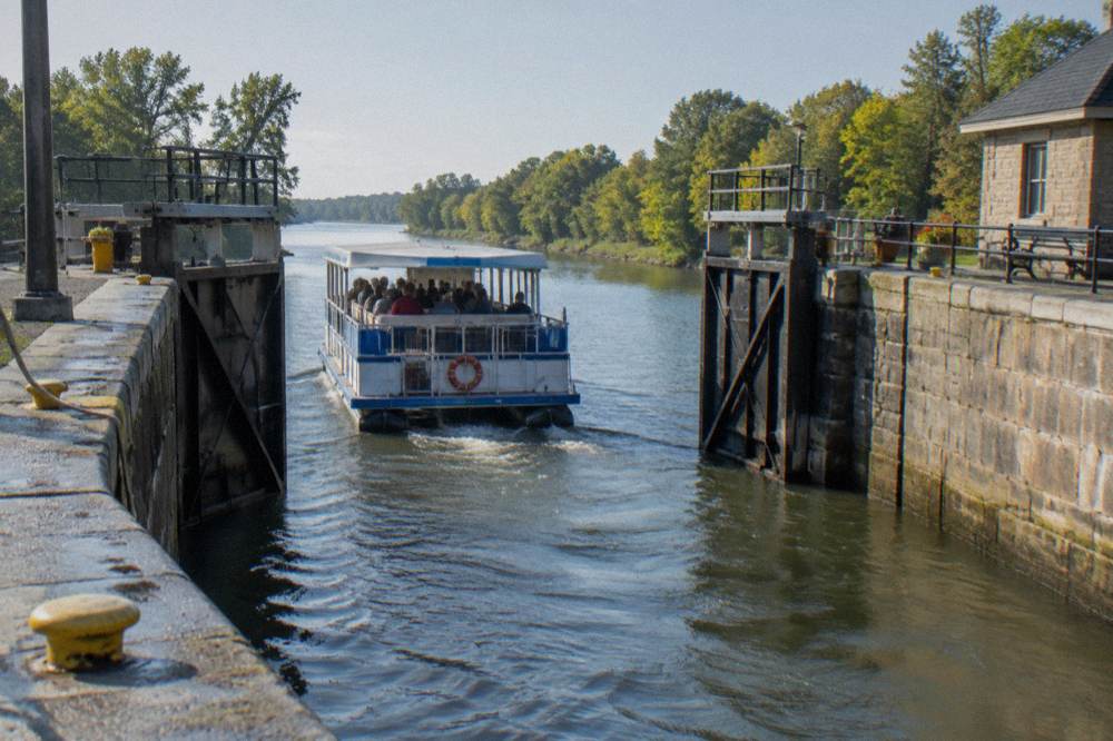 A canal tour boat leaving a lock chamber with gates opening onto the waterway beyond